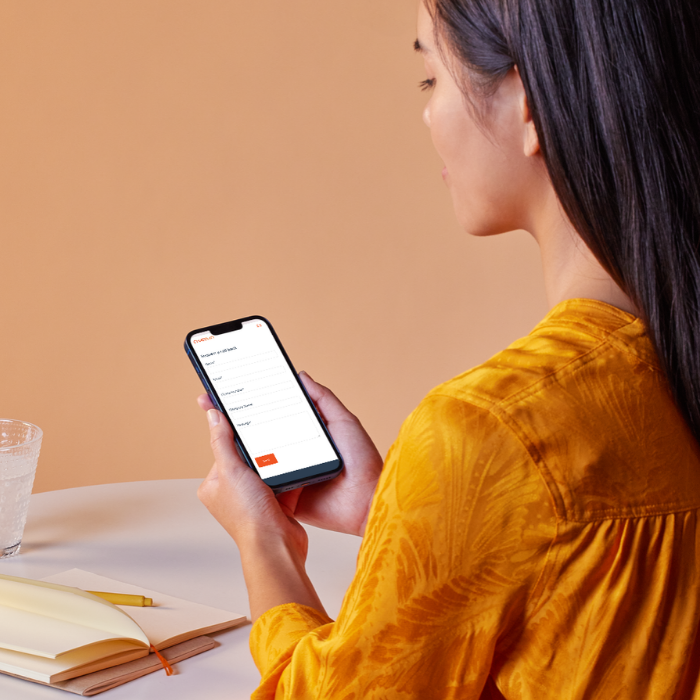 woman with brown hair and a yellow top using her mobile phone to request a phone call back from chadsan team