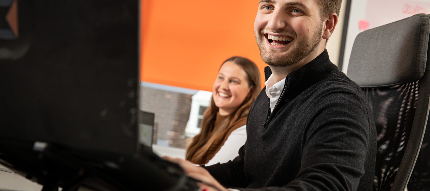 team members laughing together in the office whilst looking at their screen